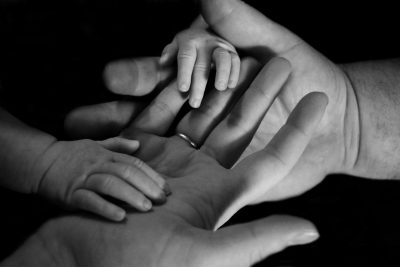 photo of parents hands with a babys hand on top.